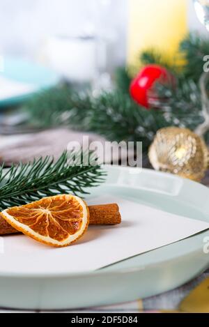 Festive Christmas and New Year details table setting with dry orange and cinnamon on a gray textile. Dining place decorated Stock Photo