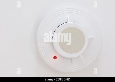 A smoke detector hangs on the white ceiling. Fire prevention device in the home or office. Fire safety system. Stock Photo
