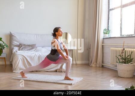 African American woman doing exercise lunges at home. Full-length photo. Stock Photo