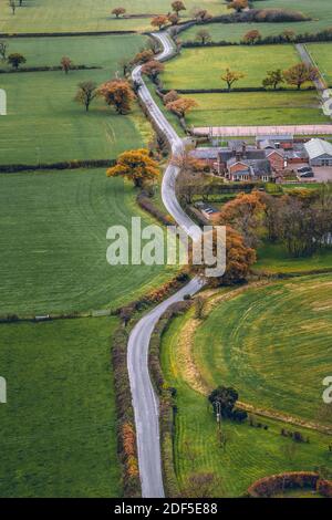 Vertical image long windy road cutting through English Countryside in Cheshire. Aerial shot during a cold day in November Stock Photo