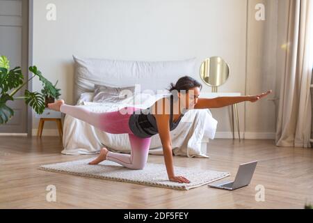 Smiling African American woman during online workout. She follows directions from a trainer on the Internet. Stock Photo