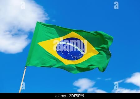 Brazilian flag waving on blue sky with some clouds. Brazil country colors. Stock Photo