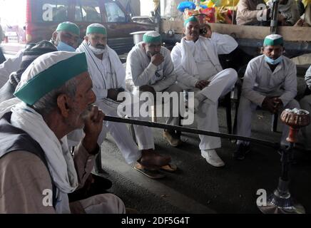 New Delhi, India. 03rd Dec, 2020. Farmers from North India's state Uttar Pradesh sit smoking a chilum blocking highway as they are not allowed to enter New Delhi to protest against the Farm Act. Protesting farmers say the new laws were passed without consultation with the people who may be affected by them. (Photo by Sondeep Shankar/Pacific Press) Credit: Pacific Press Media Production Corp./Alamy Live News Stock Photo