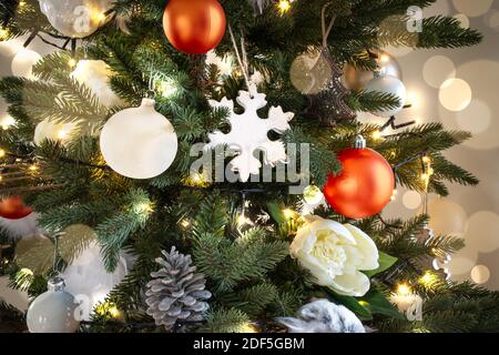 Illuminated Christmas tree with white and orange Christmas decorations and light flare. Stock Photo