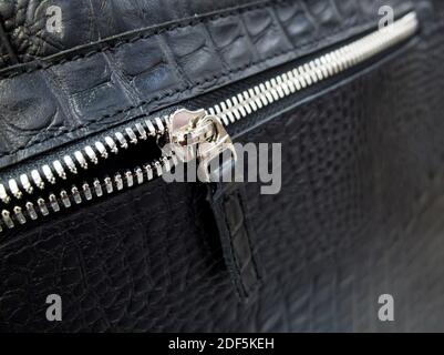 Silver-tone zip fastener on a black leather bag Stock Photo