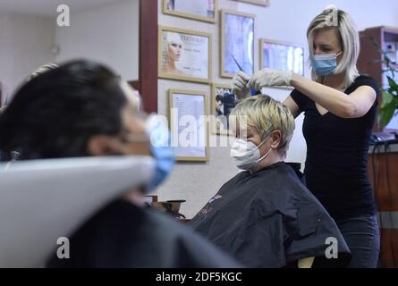 A hairdresser wearing a face mask as preventive measure cuts hair of a client wearing face mask too amid coronavirus crisis. Hair salons, restaurants  and small-scale shops reopened under strict safety measures in Trest, Czech Republic, December 3, 2020. (CTK Photo/Lubos Pavlicek) Stock Photo