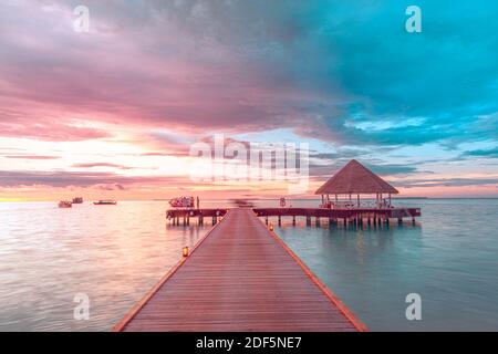 Sunset on Maldives island, luxury water villas resort and wooden pier. Beautiful sky and clouds and beach background for summer vacation holiday Stock Photo