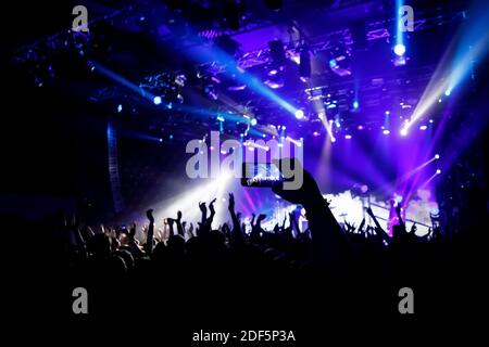 Filming a concert on mobile phone camera, blue light of stage Stock Photo