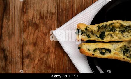 Rollini with brynza cheese and spinach on a black plate with a wooden background