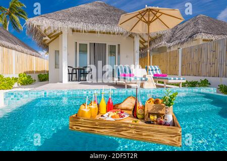Breakfast in swimming pool, floating breakfast in luxurious tropical resort. Table relaxing on calm pool water, healthy breakfast fruit plate, luxury Stock Photo