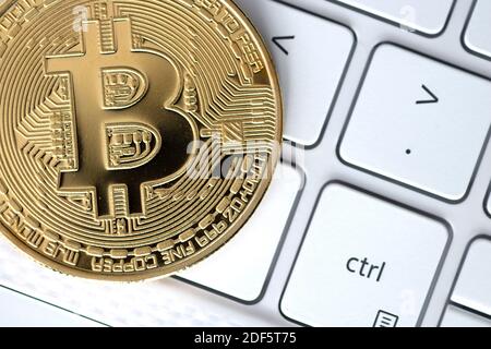 Gold bitcoin on white computer keyboard Stock Photo