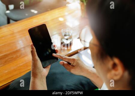 senior lady sitting in a chair and touching the screen of smartphone, online shopping concept Stock Photo