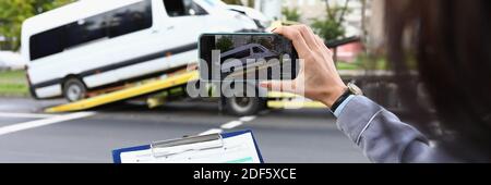 Woman insurance agent films broken minibus on smartphone Stock Photo