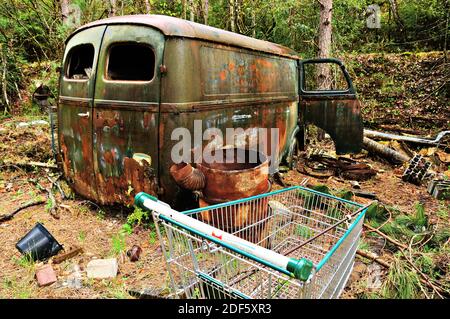 Abandoned rusty car and barrel  left in the forest. France. Stock Photo