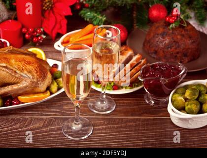 Table served for thanksgiving or Christmas dinner. Two glasses of wine or champagne. Stuffed roasted turkey in the foreground. Traditional celebrating Stock Photo