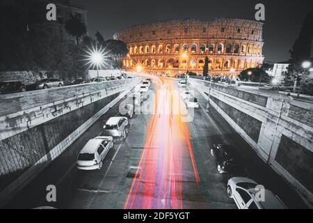 Rome, Italy. Colosseum Also Known As Flavian Amphitheatre In Evening Or Night Time. Night Traffic Light Trails Near Famous World Landmark. All colors Stock Photo