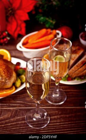 Table served for thanksgiving or Christmas dinner. Two glasses of wine or champagne. Stuffed roasted turkey in the foreground. Traditional celebrating Stock Photo