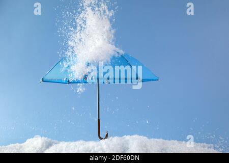 Blue umbrella on blue background with snow. Blue monday concept. Stock Photo