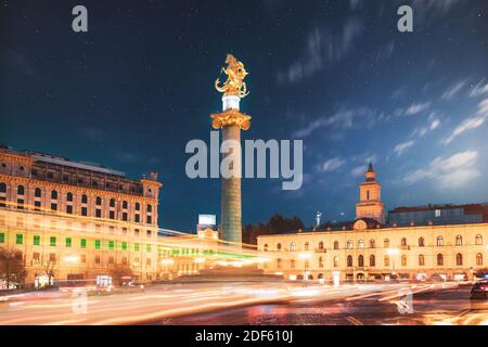 Tbilisi, Georgia. Liberty Monument Depicting St George Slaying Dragon And Tbilisi City Hall In Freedom Square In City Center. Famous Landmark In Night Stock Photo