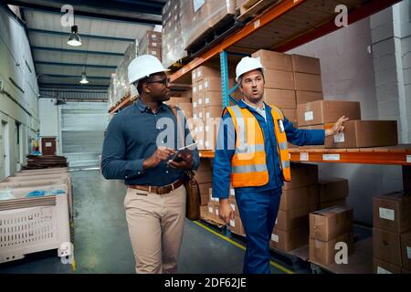 Multiracial workers discussing about warehouse stock wearing safety helmets Stock Photo