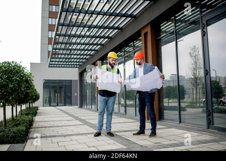 Two architects examining a blueprint and working on a building project. Stock Photo