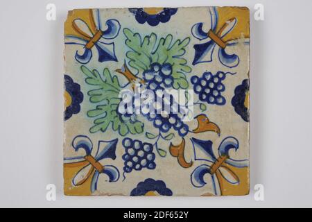 wall tile, Anonymous, first half of the 17th century, tin glaze, earthenware, General: 13.2 x 13.4 x 1.8cm (132 x 134 x 18mm), bunch of grapes, Northern Netherlands, Wall tile of earthenware covered with tin glaze. Multicolor painted in blue, orange brown and green. The decoration consists of symmetrical bunches of grapes with leaves. The tile has a lily as a corner motif and half a flower on the edges, 1985 Stock Photo