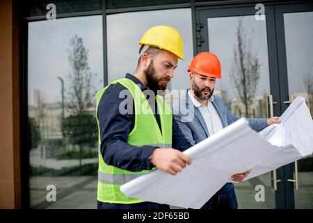 Two architects examining a blueprint and working on a building project. Stock Photo