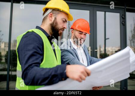 Two architects examining a blueprint and working on a building project. Stock Photo