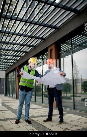 Two architects examining a blueprint and working on a building project. Stock Photo