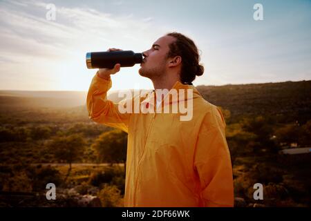 Portrait of young man drinking water from bottle while resting after run Stock Photo