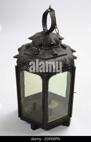 lantern, Anonymous, 18th century, wood, iron, forged, Hexagonal candle lantern made of black painted sheet iron with straight walls. The six walls, reinforced with rods at the corners, have arched windows, one of which is a hinged door. One of the windows is missing. The bottom is mounted on a wooden supporting cross and on the inside there are three cylindrical candle holders. The pagoda-shaped roof, which is profiled in three layers, has arch-shaped, round-covered ventilation holes. The bottom layer two holes per side and the two above one. On top of the lantern roof is a flat sheet iron Stock Photo