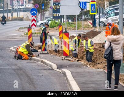 Bucharest/Romania - 11.17.2020: Group of workers with shovels digging a trench along the road in Bucharest. Stock Photo