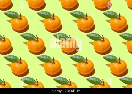 Seamless pattern of ripe tangerines with green leaves on a green background Stock Photo
