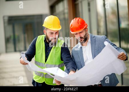 Two architects examining a blueprint and working on a building project. Stock Photo