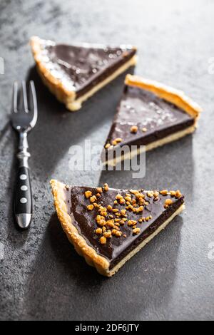 Sweet chocolate pie with crushed nuts on black table. Stock Photo