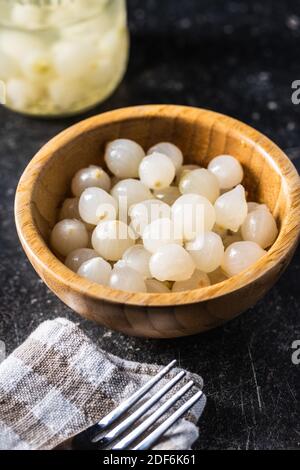 Pickled mini baby onions in wooden bowl. Stock Photo