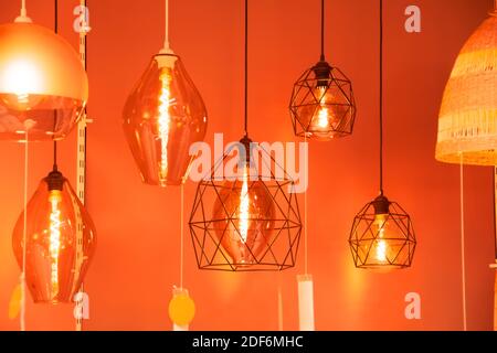 Many pendant lamps in different geometric shapes with a vintage glowing spiral of warm light Stock Photo