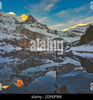Scenic landscape of Switzerland with snow, mountain and lake in winter.  Places to visit in Kandersteg. Reflection of mountain and sky on lake water.