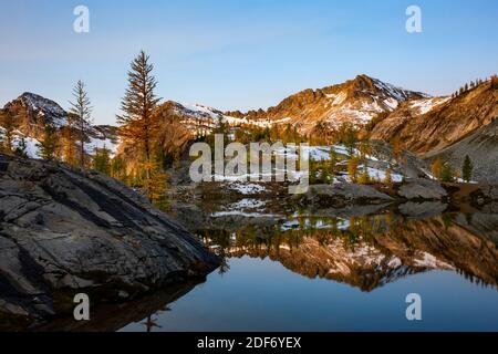 WA18642-00...WASHINGTON - The Entiat Mountains reflecting in Lower Ice Lake brighten by Alpine Larch trees in fall color, Glacier Peak Wilderness. Stock Photo