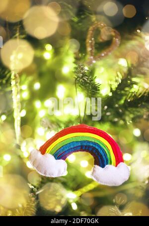 New Year's colourful rainbow toy on a Christmas tree with garlands. Stock Photo