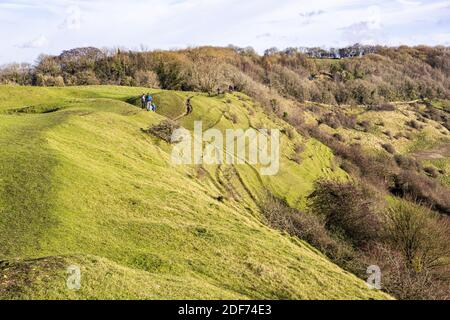 Hikers walking along the rampart of a slight univallate Iron Age hillfort on Ring Hill at the Cotswold viewpoint of Haresfield Beacon, Gloucestershire Stock Photo