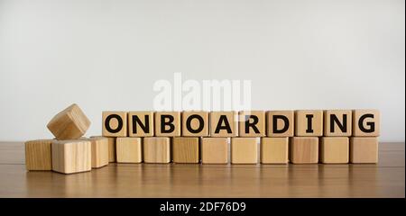 Onboarding symbol. 'Onboarding' written on wooden blocks. Business and onboarding concept. Beautiful wooden table, white background. Copy space. Stock Photo