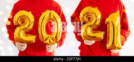 Hands holding the Golden numbers 2021 from new year's balls of yellow metallic color. Banner Stock Photo