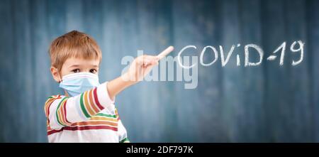 Boy in medical face protection mask indoors on blue background. Stock Photo