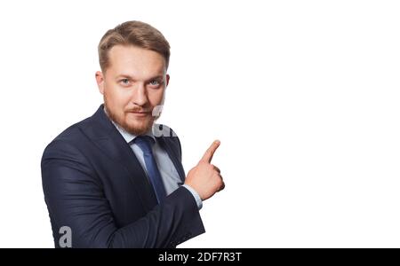 Serious man pointing away while standing against white background. Stock Photo