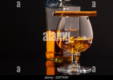 Burning cigar and glass of whisky on black background Stock Photo