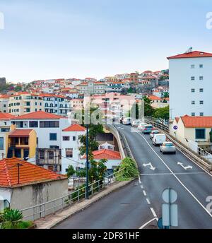 Aerial Funchal cityscape, traffic on hill road, residential houses with red rooftops, Madeira, Portugal Stock Photo