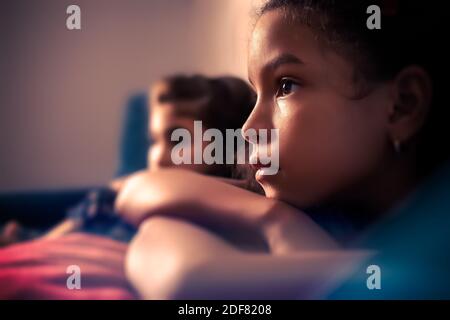 Portrait of two small girls watching TV - with a shallow depth of field Stock Photo