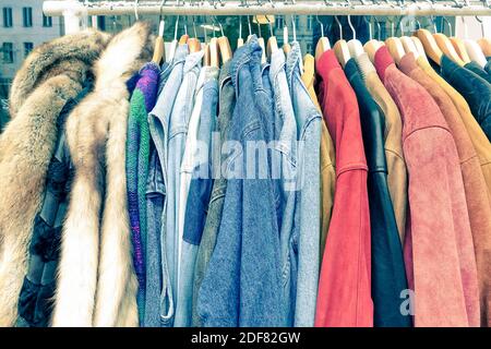 Vintage second hand clothes hanging on shop rack at weekly flea market - Hipster wardrobe sale concept and alternative retro moda fashion styling Stock Photo