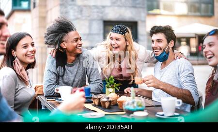 Multiracial people having fun drinking at outside coffeehouse - Young friends talking together at restaurant - New normal lifestyle concept